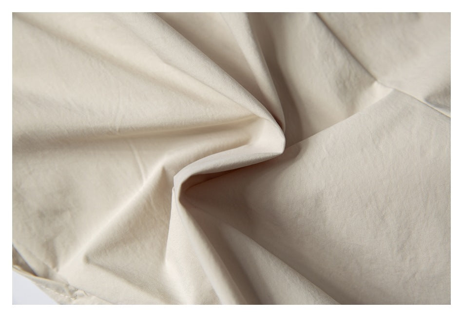 Extreme close-up of the cream shorts fabric gathered into soft folds.