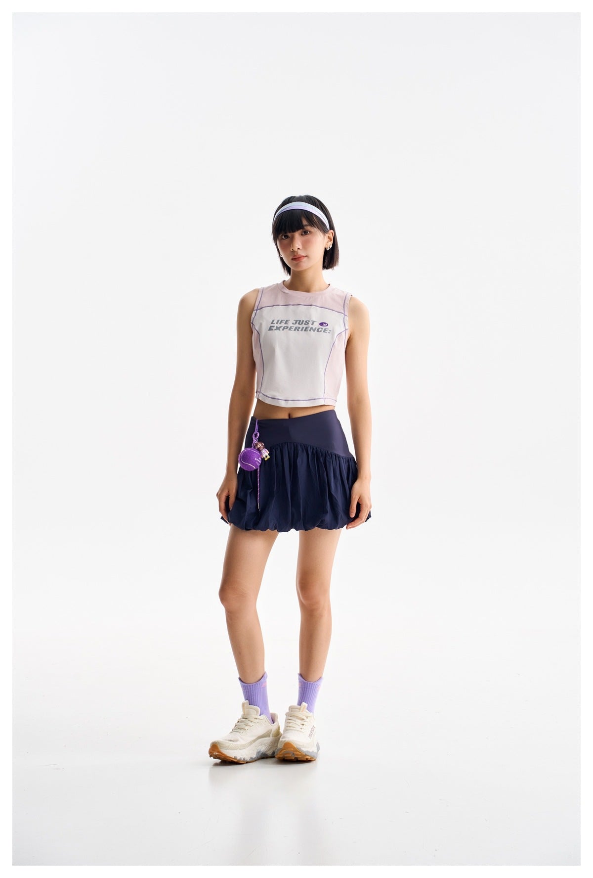 A model wears a pale pink sleeveless crop top and a navy bubble skirt with a wide waistband.