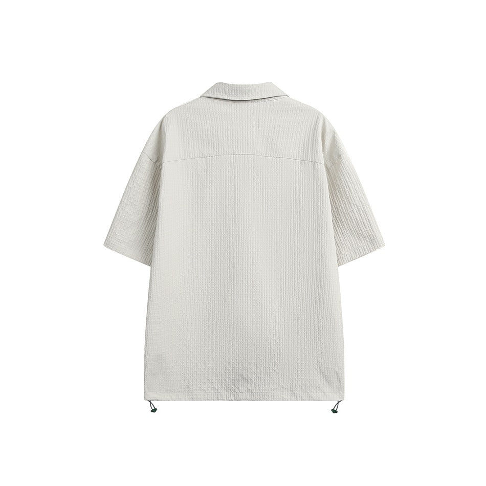 Back view of an ivory short-sleeve collared shirt with a straight hem and adjustable drawcords at the sides.