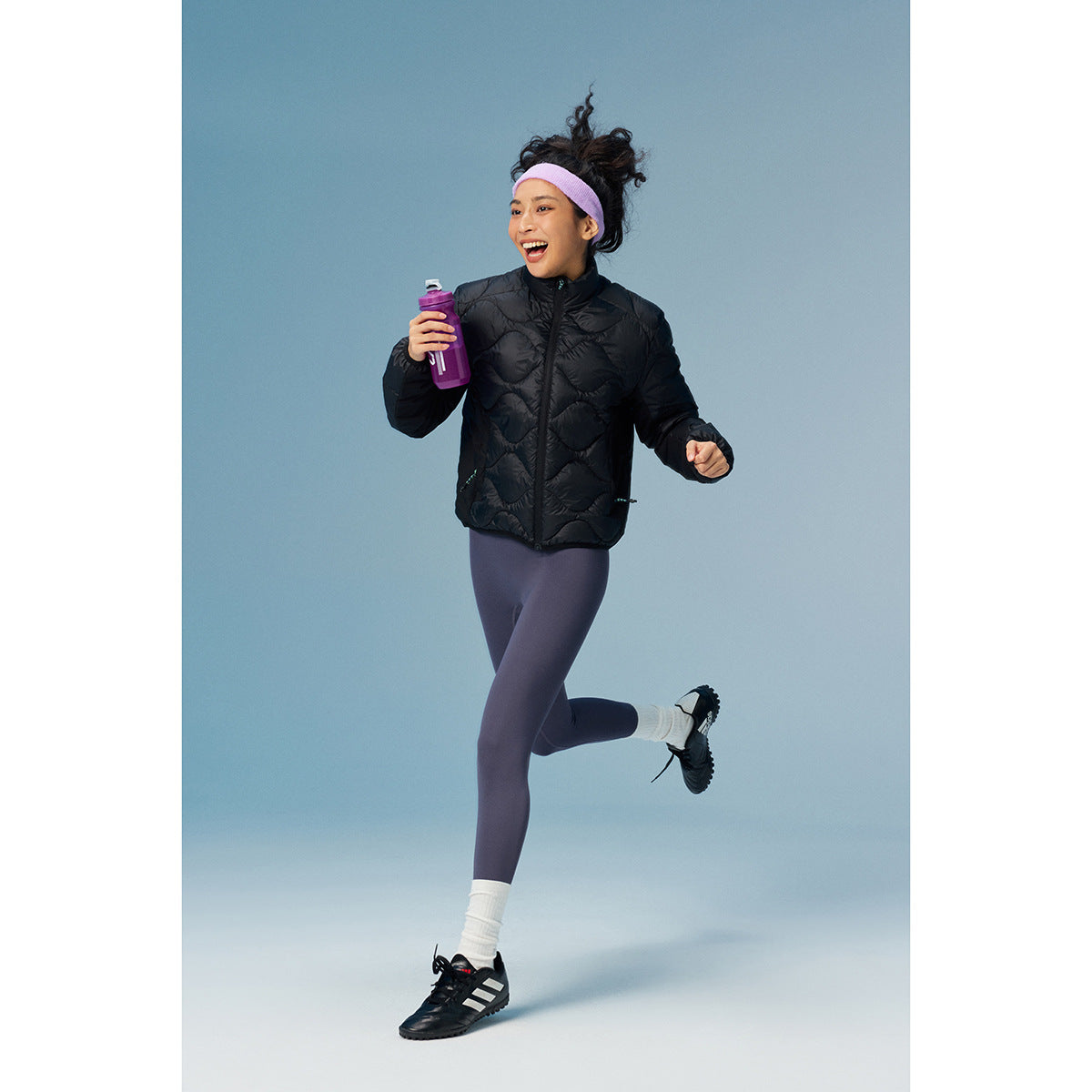 Runner wearing a black quilted zip jacket with purple leggings and a lavender headband.
