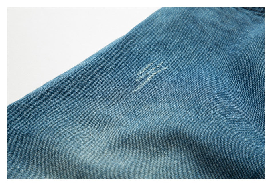 Close-up of blue denim fabric with a small cluster of distressed slashes.