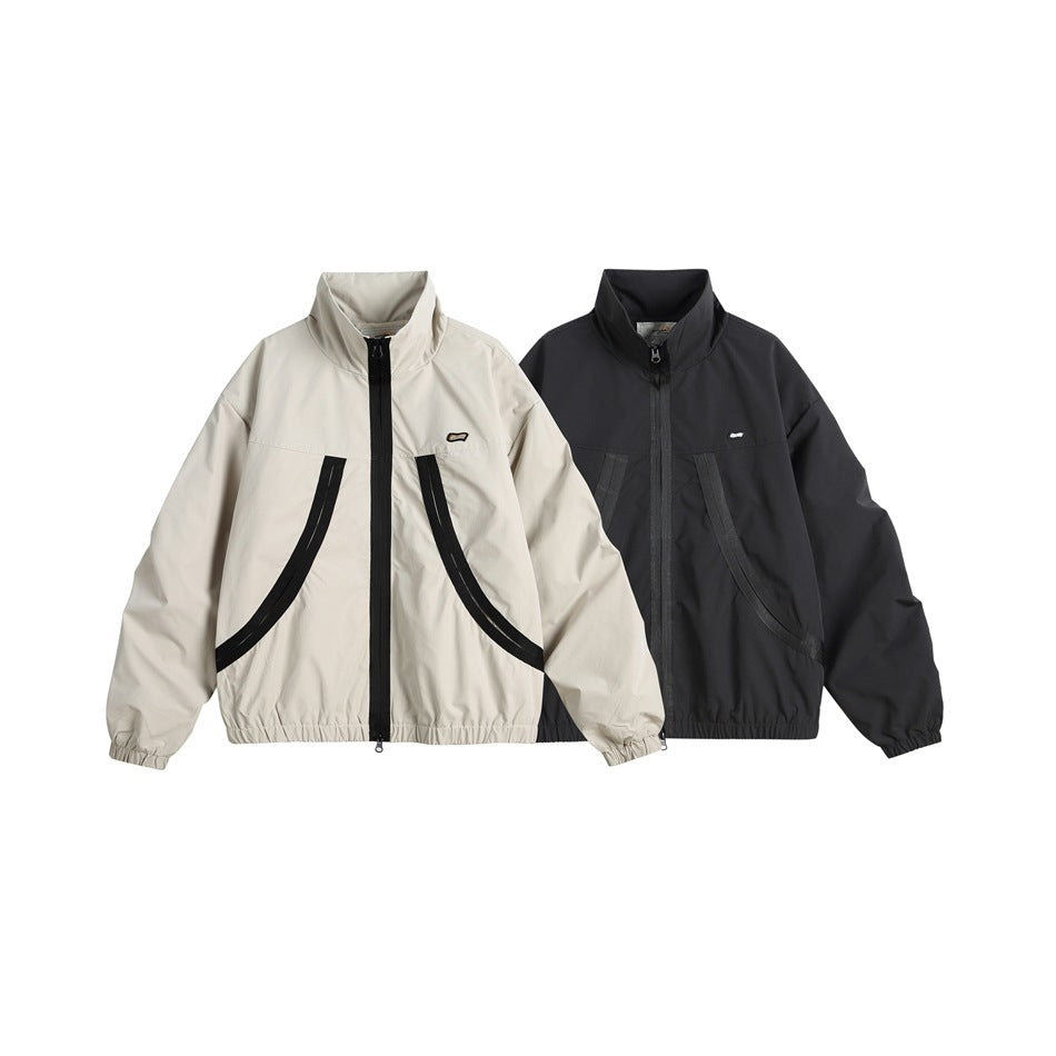 Two zip-up jackets shown from the front: one off-white and one dark charcoal, both with curved pockets and high collars.