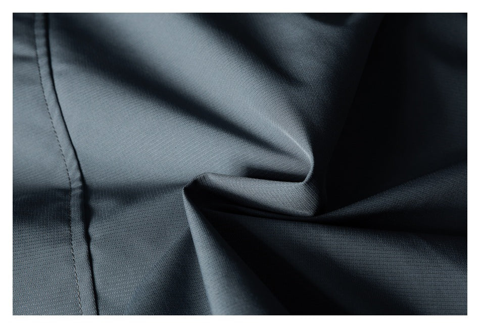 Close-up of dark charcoal fabric with a fine textured weave and stitched seam.