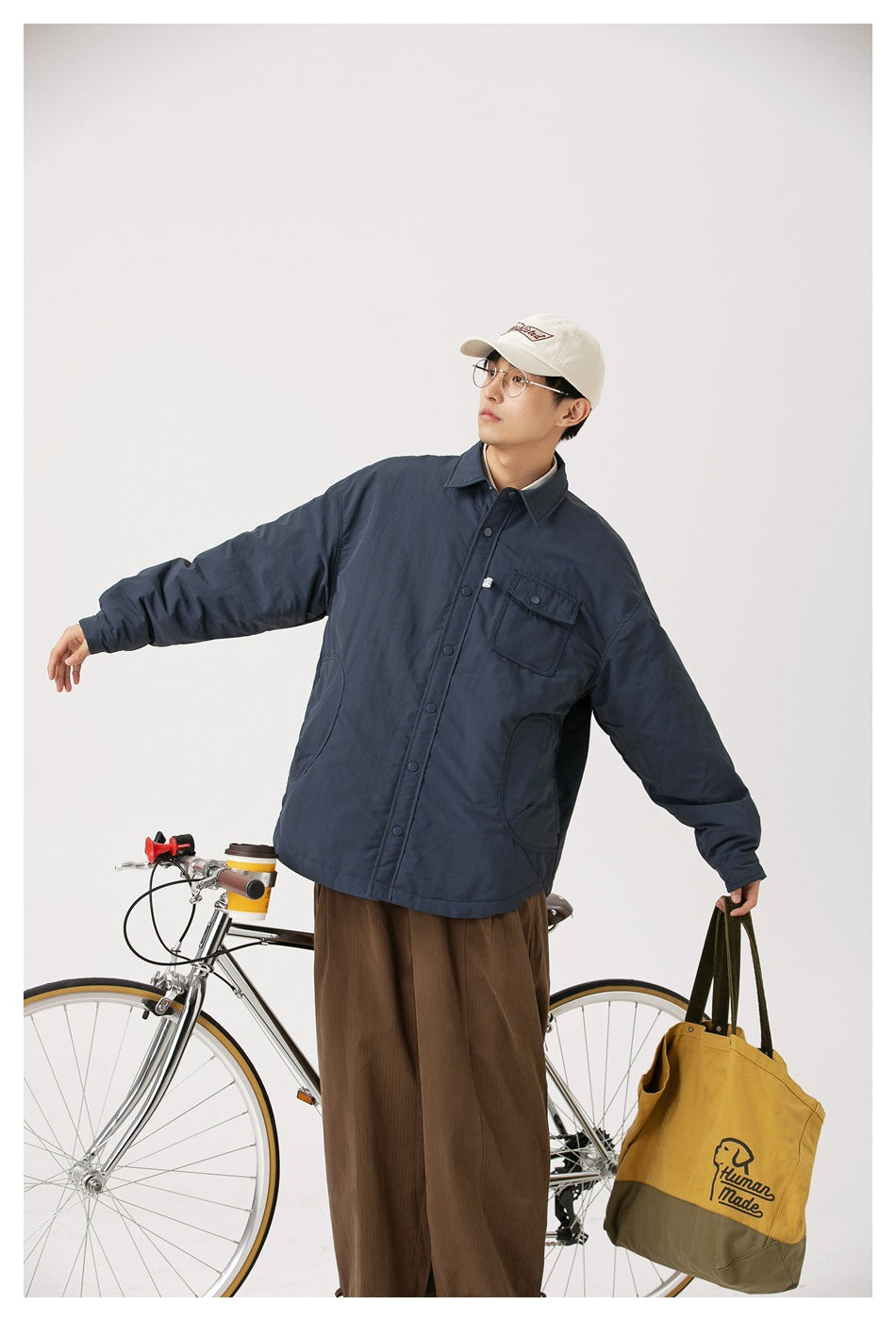 Model wearing an oversized navy button-front jacket with a flap chest pocket and rounded lower pockets.