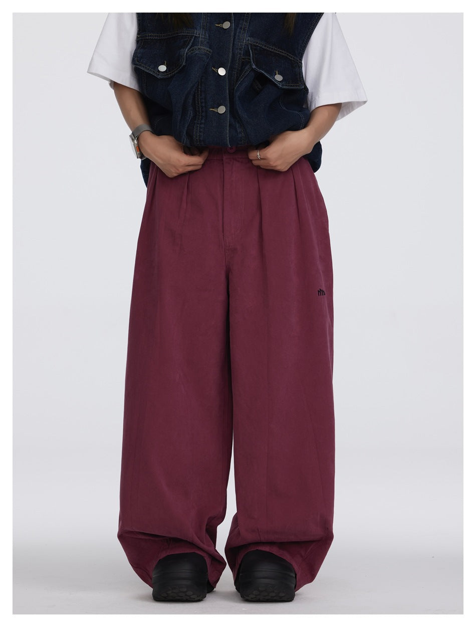 Front view of a model wearing loose burgundy wide-leg pants with a dark denim vest and white T-shirt.