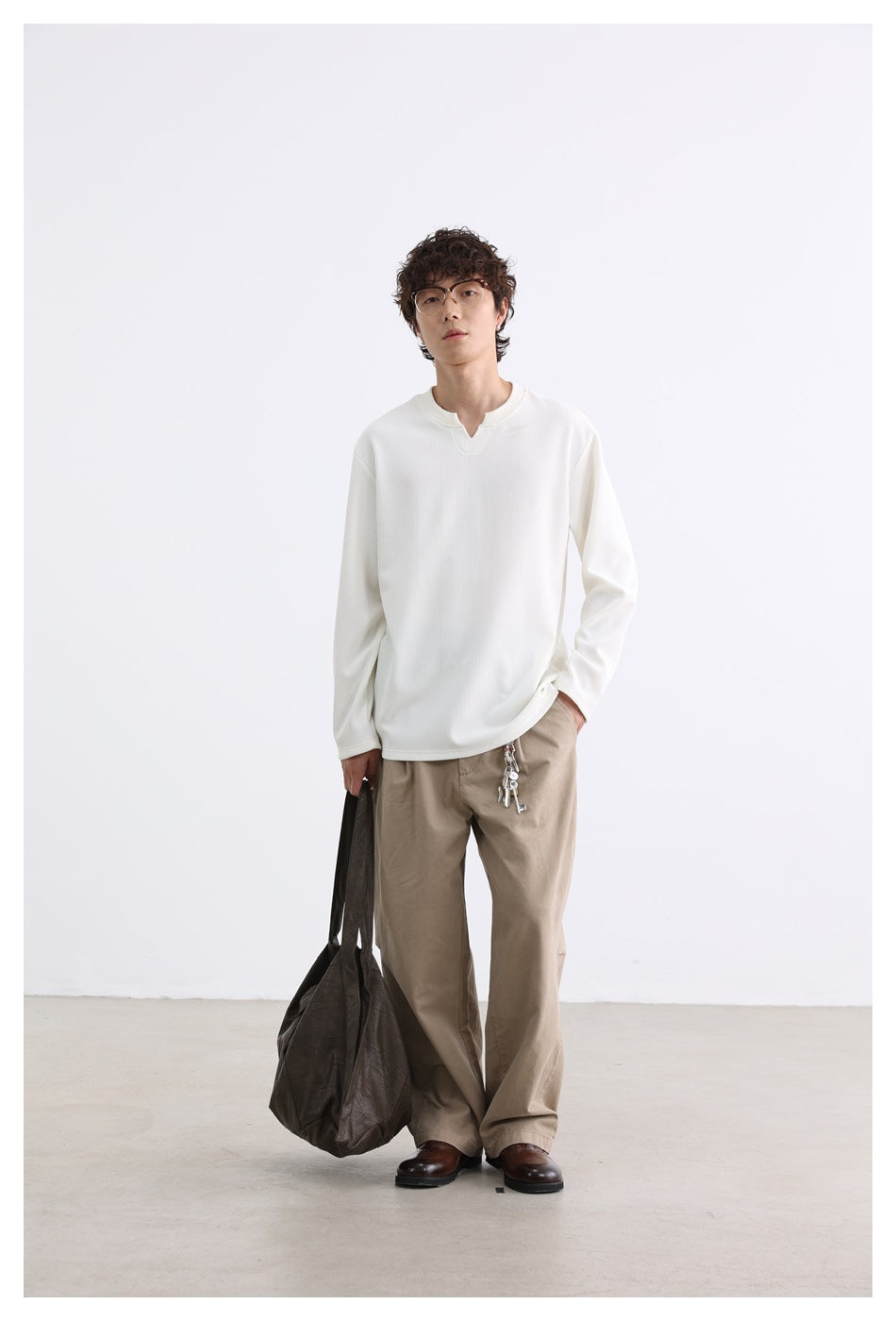 Full-length model wearing an ivory long-sleeve notched-neck top, beige trousers, and brown shoes.