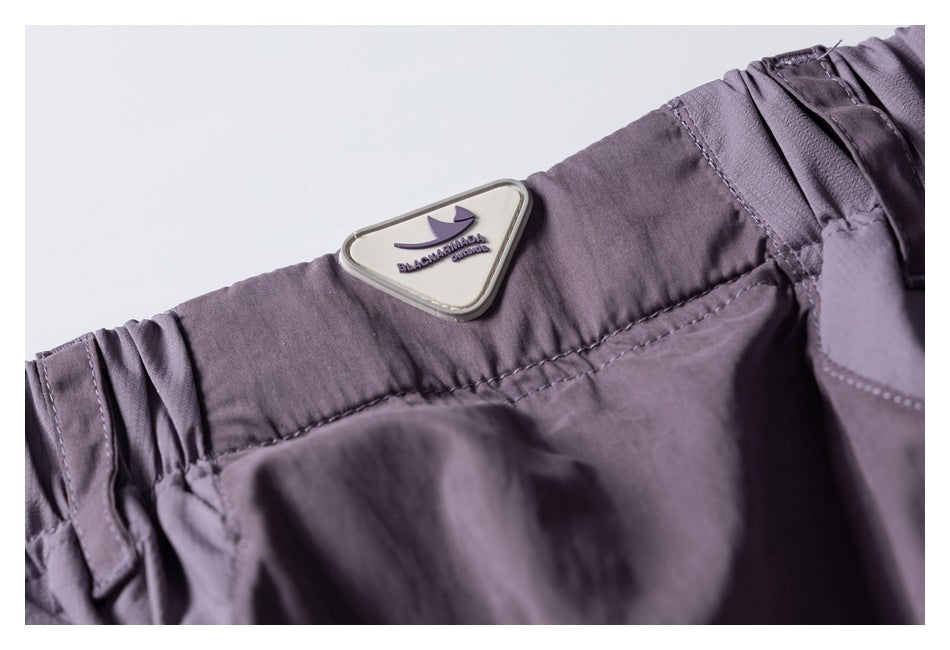Close-up of the lavender pants' waistband and sewn-on triangular brand patch.