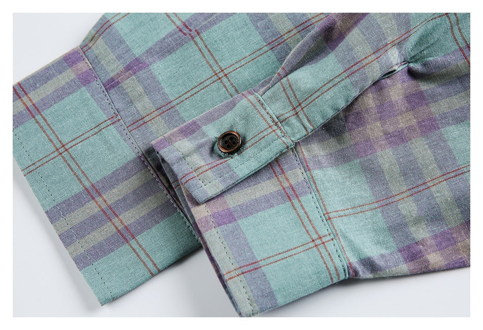 Close-up of a buttoned cuff on a mint and lavender plaid shirt with thin rust-red lines.