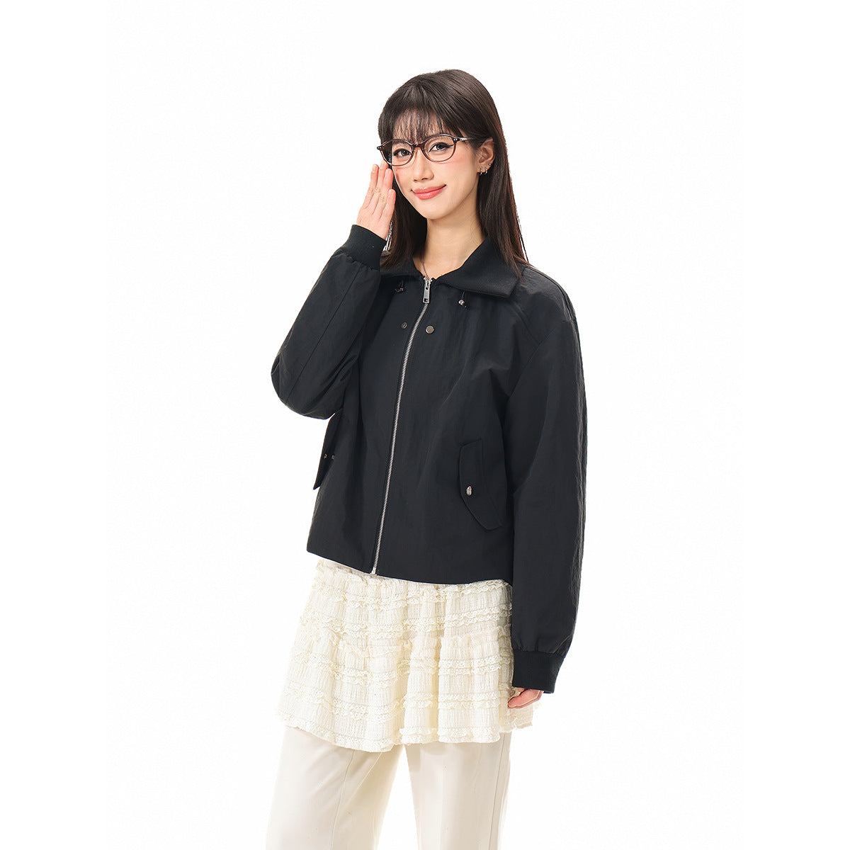 Closer view of a model wearing a black collared zip-front jacket with long sleeves and flap pockets.