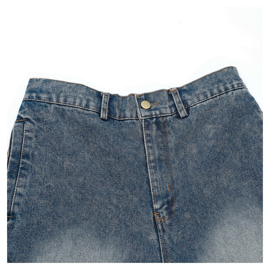 Cropped front view of blue denim pants showing the waistband, belt loops, button, and fly.