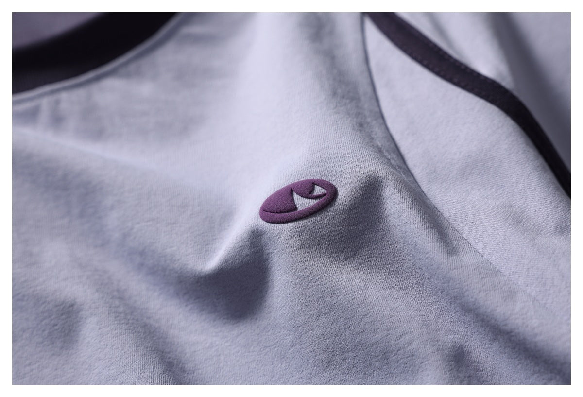 Close-up of a small purple embroidered emblem on the light gray shirt.