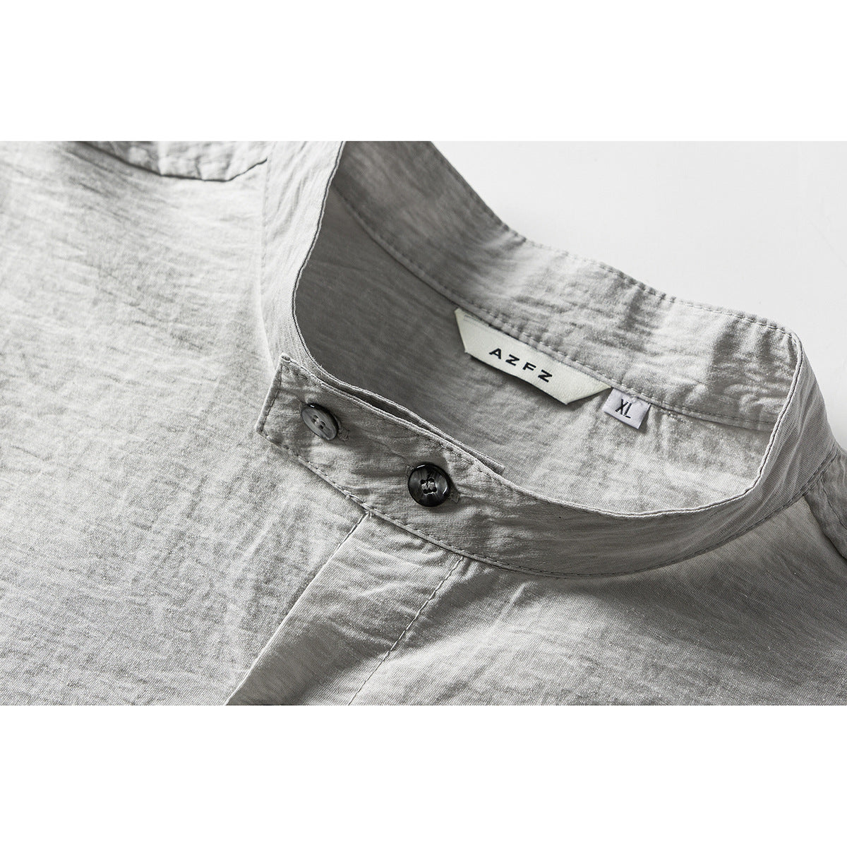 Close-up of a light gray shirt's band collar, two dark buttons, and sewn-in neck and size labels.