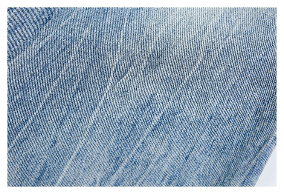 Close-up of mottled light and medium blue denim with a faded wash.