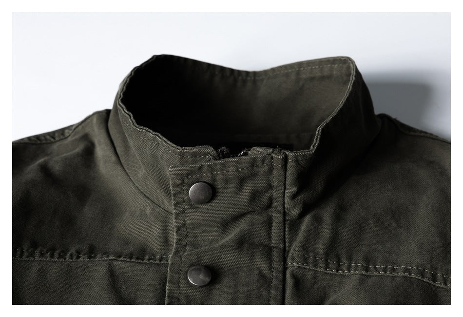 Close-up of an olive drab jacket’s stand collar, snap-button placket and shoulder seams.