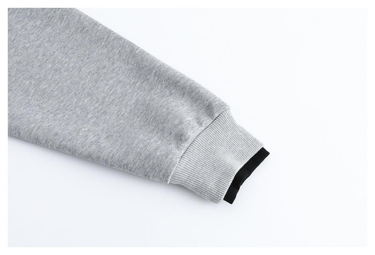 Close-up of a light gray sweatshirt sleeve ending in a ribbed cuff with a black inner layer visible.