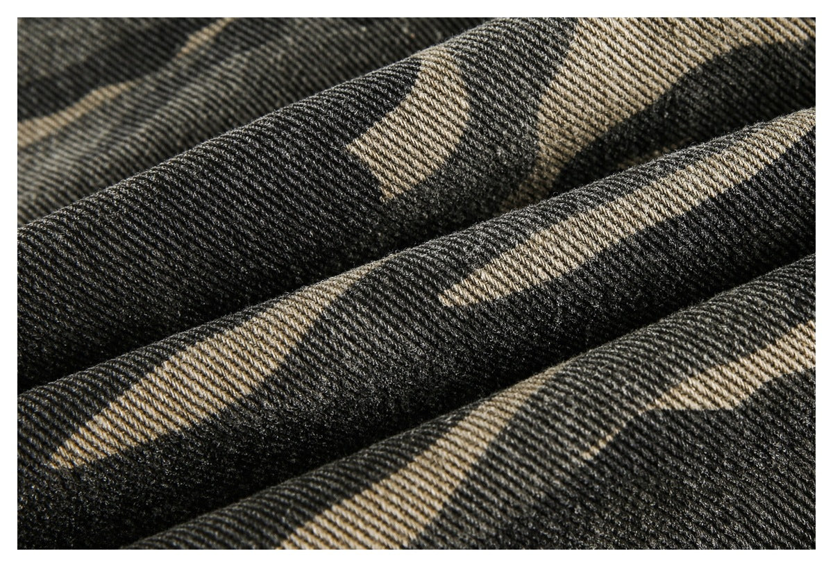 Macro view of the black and tan camouflage fabric, showing its diagonal denim weave and textured surface.