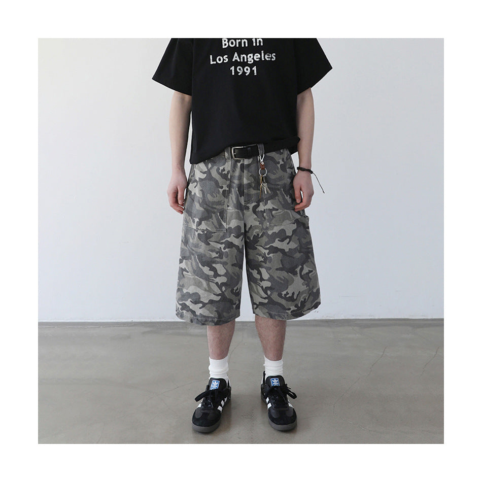 Person wearing camouflage knee-length shorts with a black belt, black graphic T-shirt, white socks and black sneakers