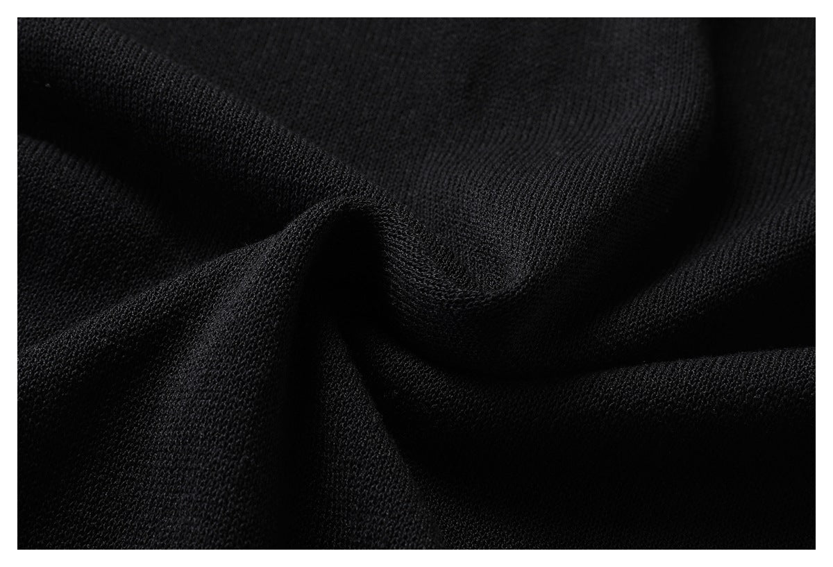 Close-up of black knit fabric draped into folds, showing its surface texture.