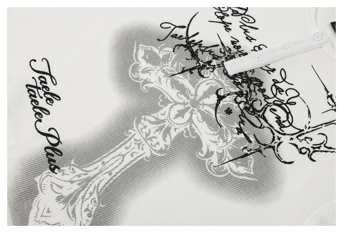 Close-up of a white garment with black script and gray ornamental print, plus small white buttons.
