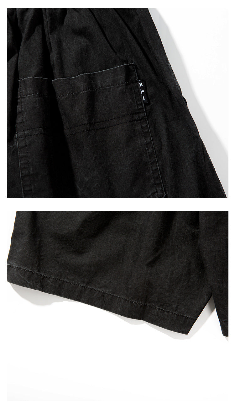 Close-up of a large stitched patch pocket and the hem of black shorts.