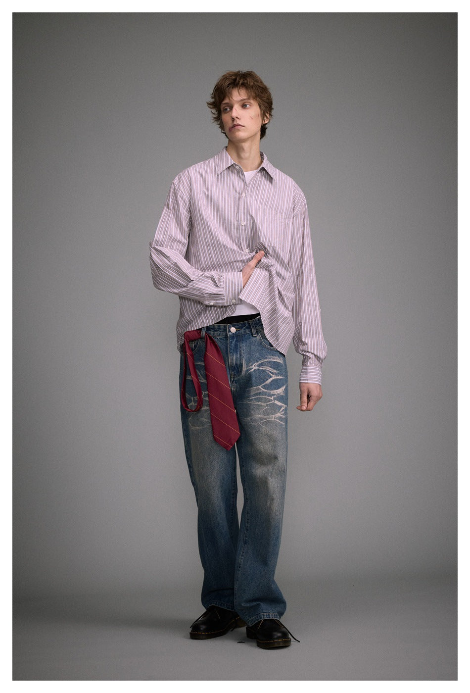 Full-length front view of a model in a pink-and-white striped shirt and distressed wide-leg blue jeans.