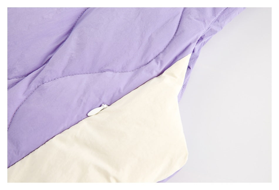 Close-up of a lavender quilted jacket panel with a white pocket section and small zipper pull.