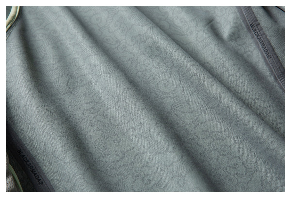 Close-up of gray fabric with an intricate swirling pattern and branded seam tape.