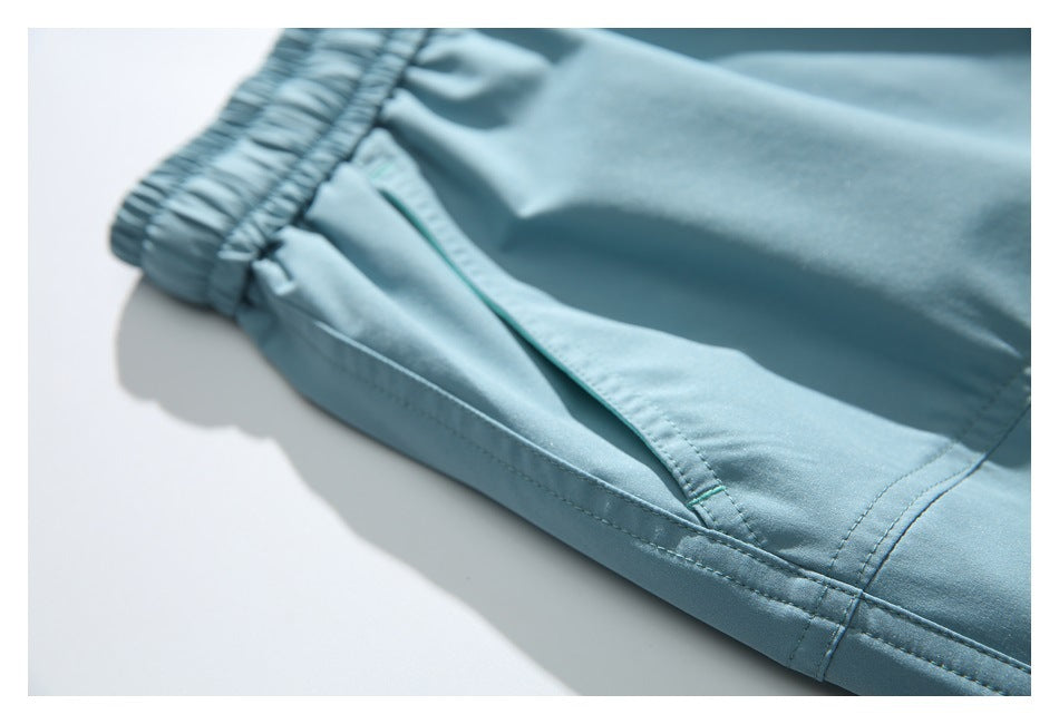 Close-up of pale blue shorts showing a slanted pocket opening, stitching, and hem.