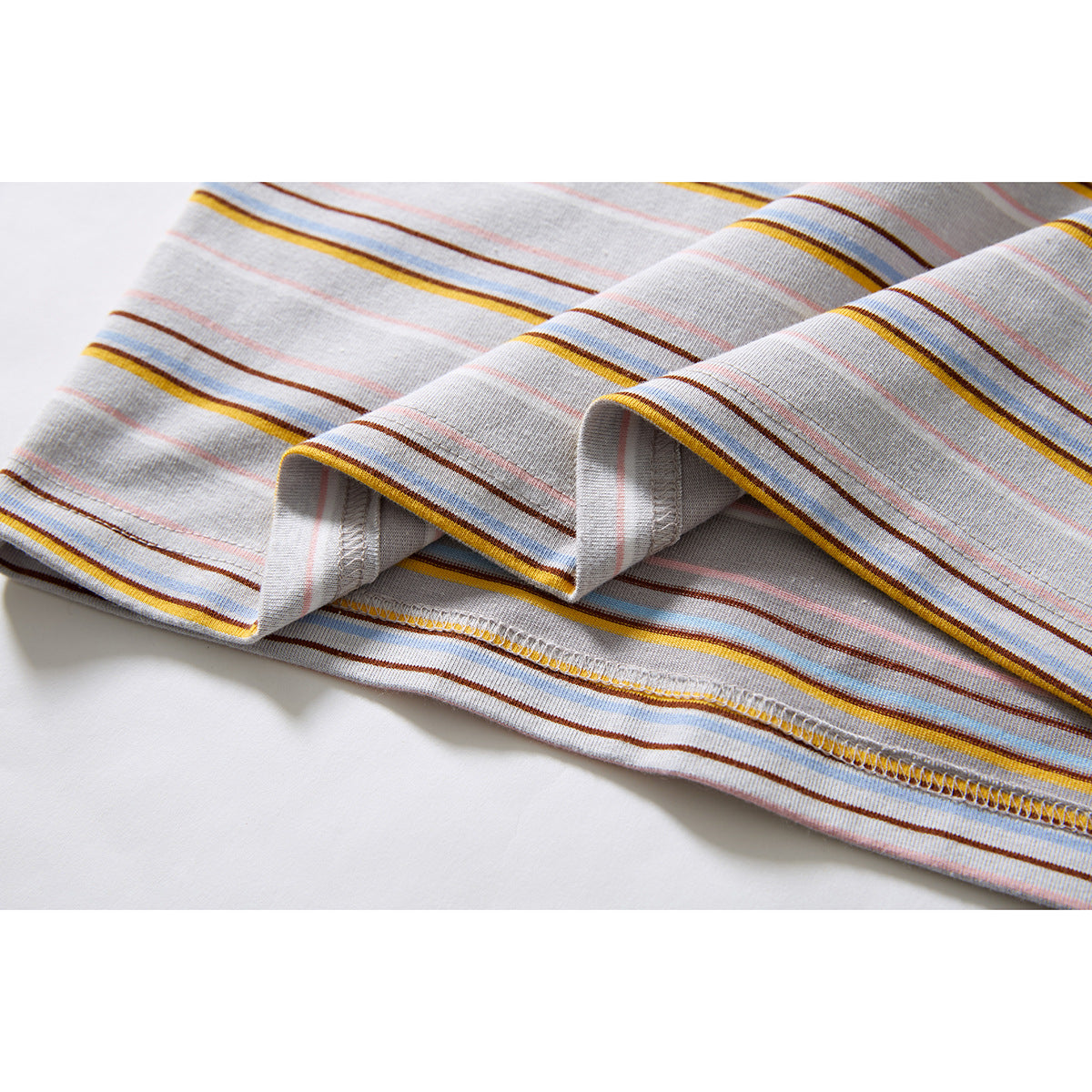 Close-up of the striped light gray T-shirt's folded hem and overlock stitching.
