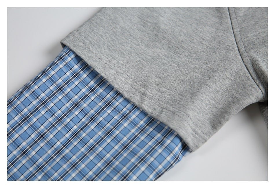Close-up showing blue plaid fabric beneath a gray shirt sleeve.