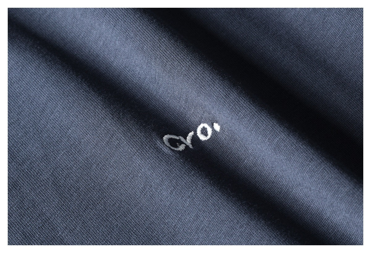Close-up of dark navy fabric with a small white embroidered mark.
