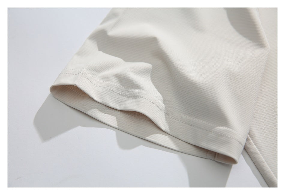 Close-up of the ivory T-shirt's short sleeve hem and stitching.