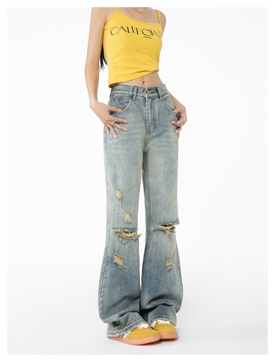 Cropped front view of a model wearing distressed light-wash wide-leg jeans and a yellow printed camisole.