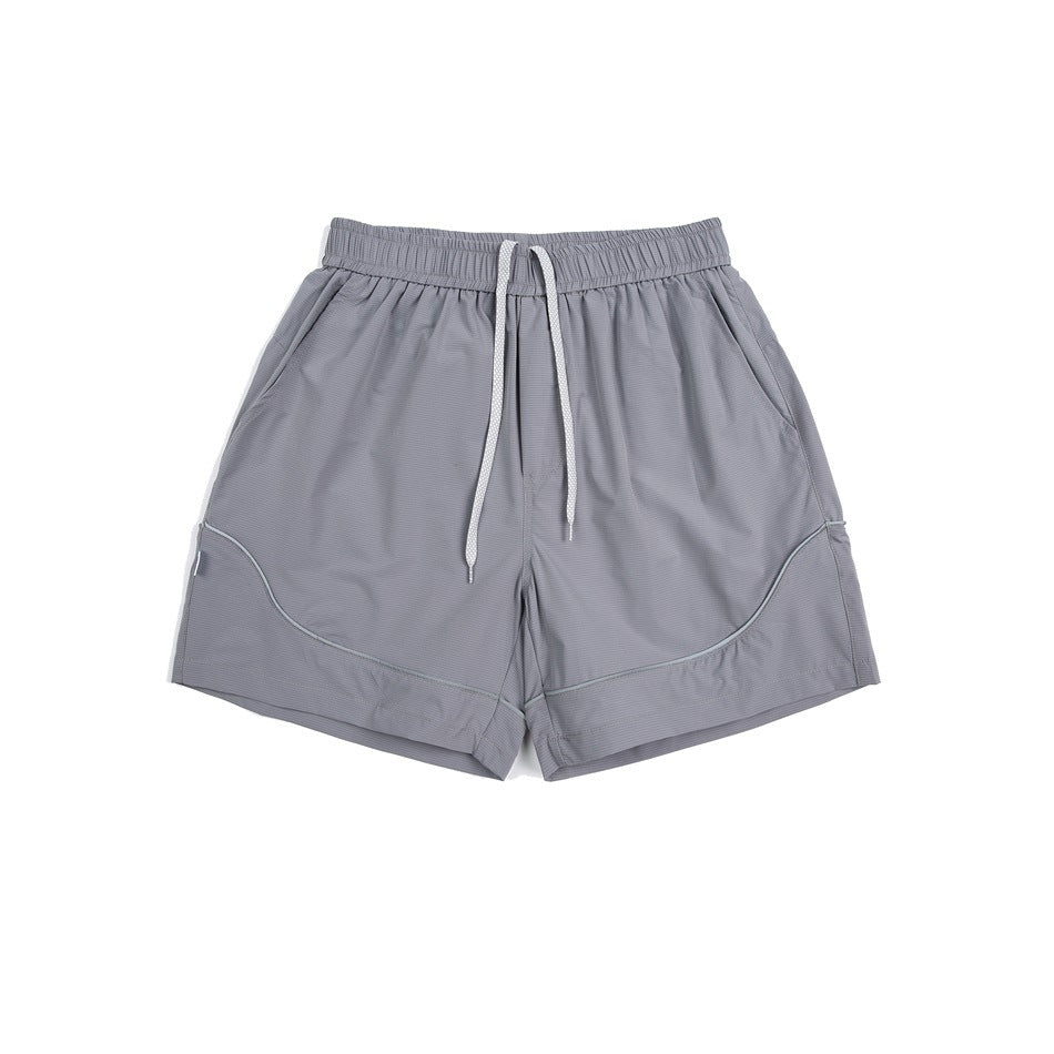 Gray elastic-waist shorts with white drawstring, side pockets and curved piping, flat lay front view