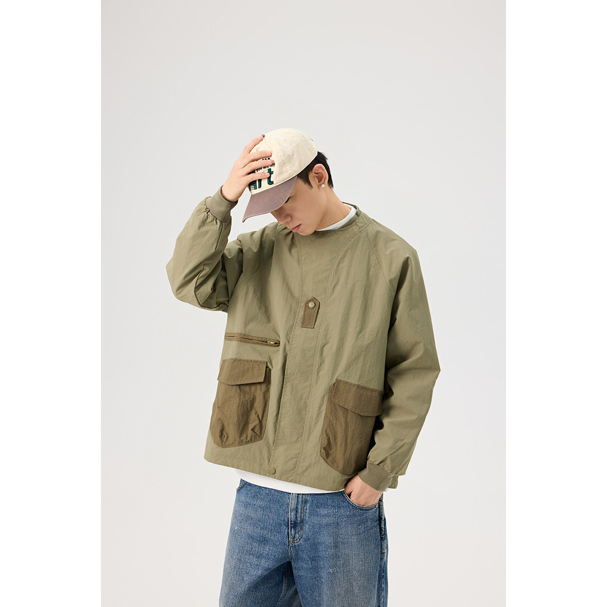 Close view of a model wearing an olive jacket with brown utility pockets and a front snap detail.
