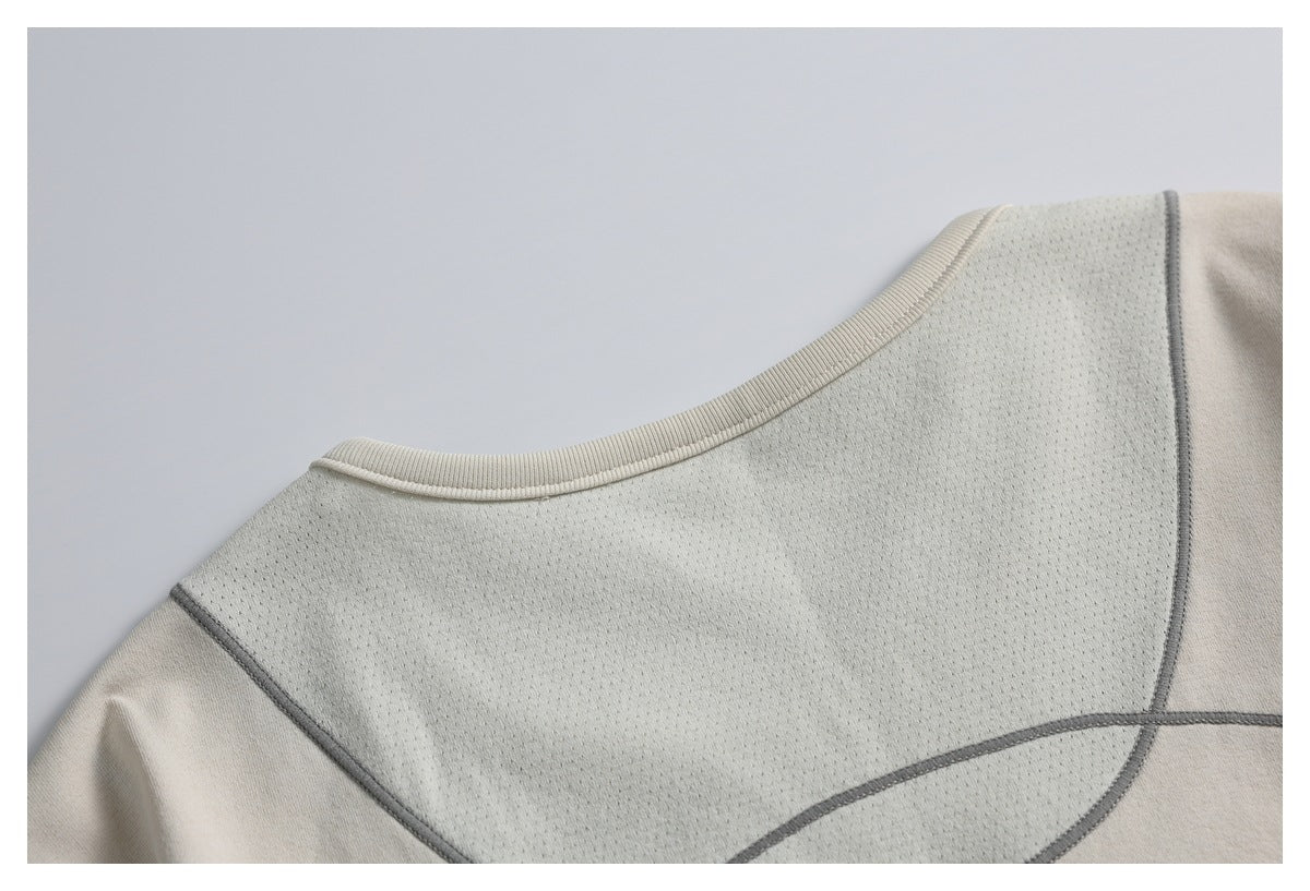 Close-up of a light beige top's rounded neckline and perforated chest panel with dark gray seam piping.