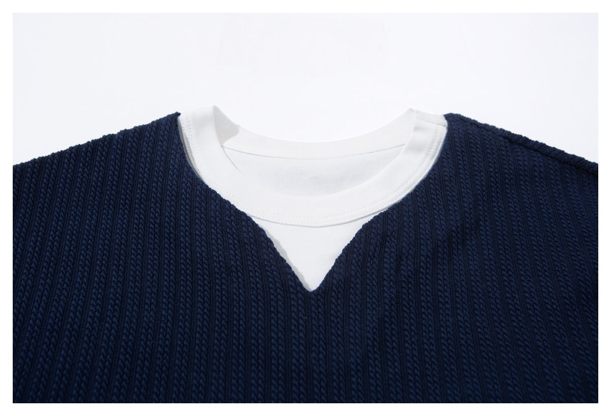 Close-up of a navy ribbed top's neckline with a white crew-neck layer and triangular insert.