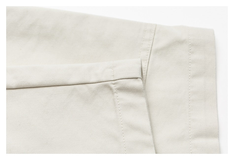 Close-up of an ivory trouser leg edge with a folded seam and parallel stitching.