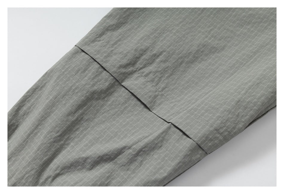 Close-up of a diagonal seam across gray grid-patterned fabric.