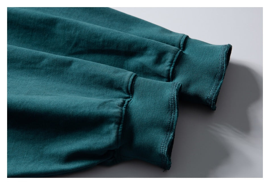 Close-up of two dark teal sleeve cuffs with ribbed bands and stitching.