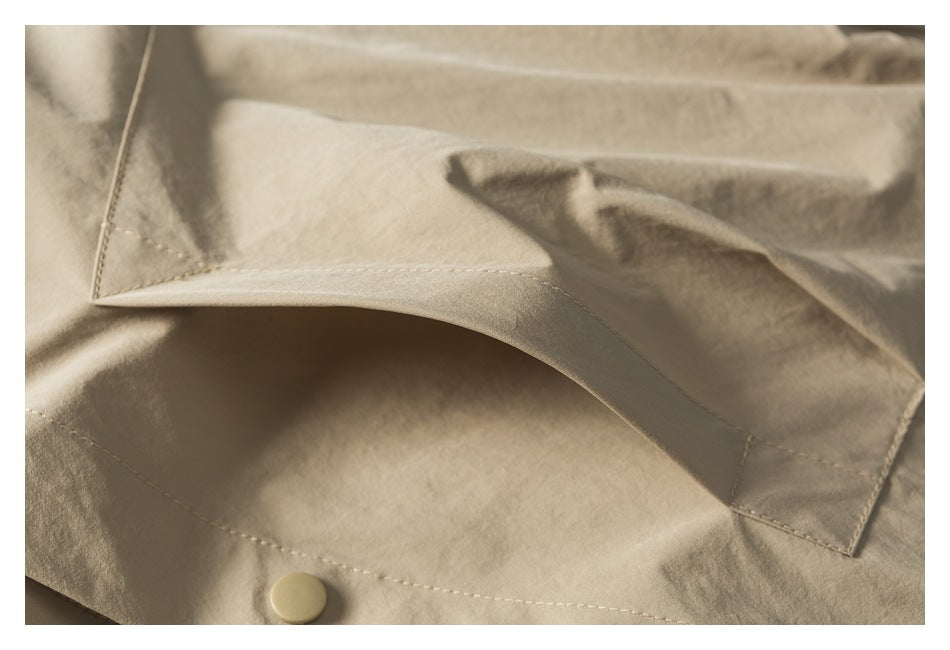 Close-up of a light tan garment collar with stitched edges and a matching button.