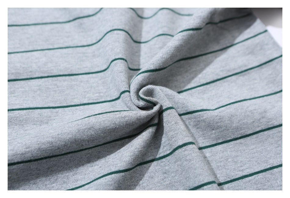 Close-up of gray fabric with narrow green stripes gathered into folds.