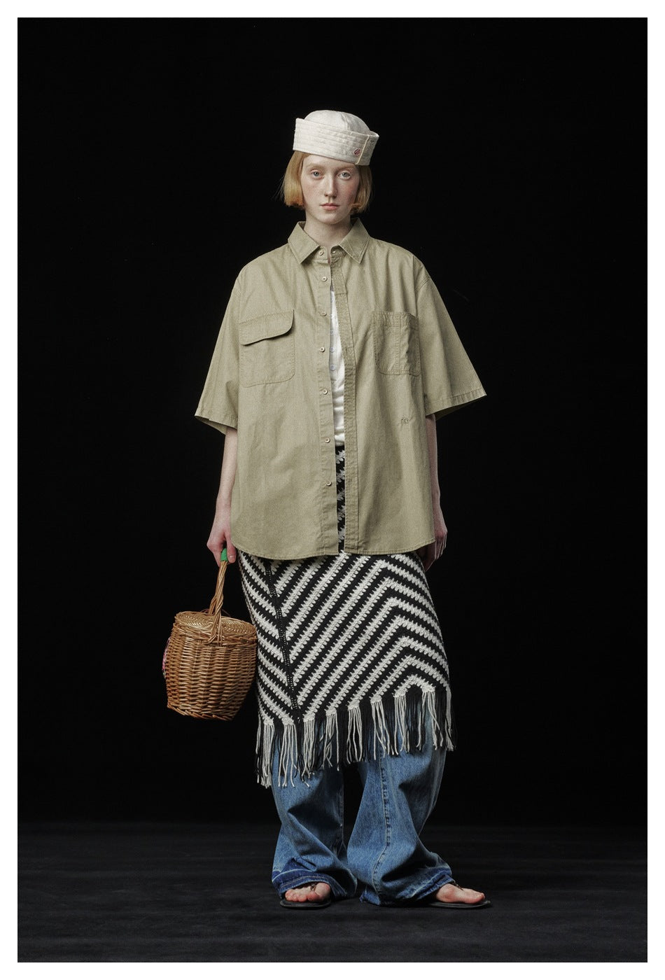 Model wearing a khaki short-sleeve work shirt over a white top with a striped fringe skirt and wide jeans
