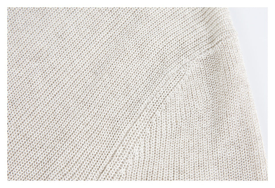 Close-up of an ivory open-knit sweater showing its textured stitches and a diagonal seam.