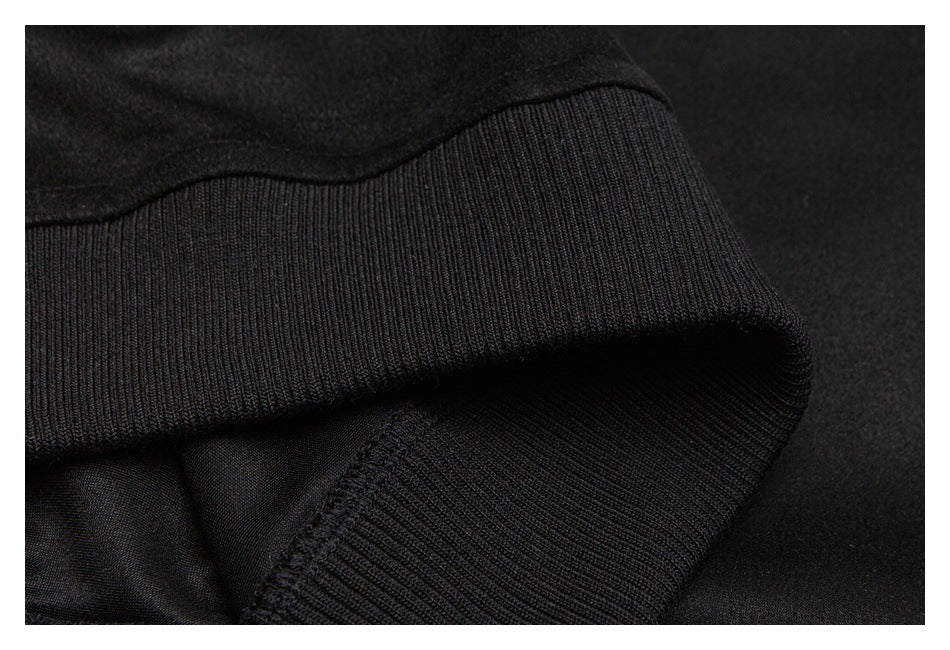 Close-up of black ribbed garment trim folded over dark fabric, showing the stitching and knit ribs.