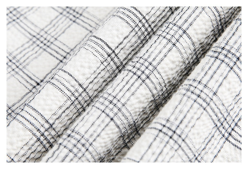 Macro view of the textured off-white fabric and intersecting black and gray plaid lines.