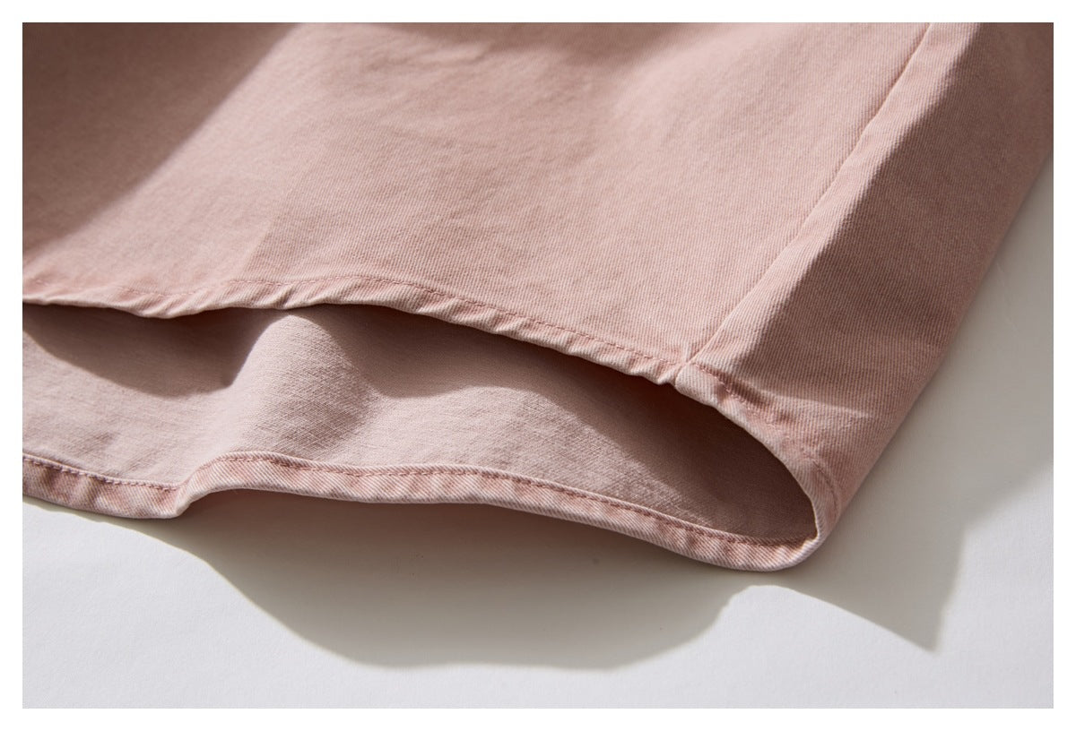 Close-up of the dusty rose shirt's curved hem and stitched edge.