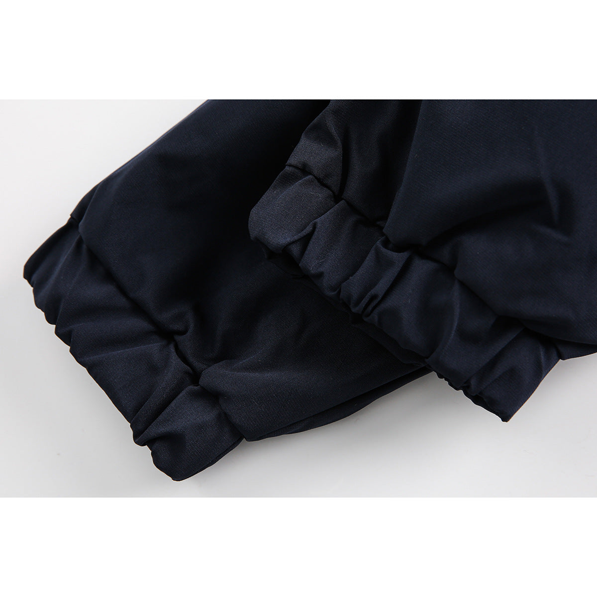 Close-up of gathered elastic sections on a dark navy jacket.