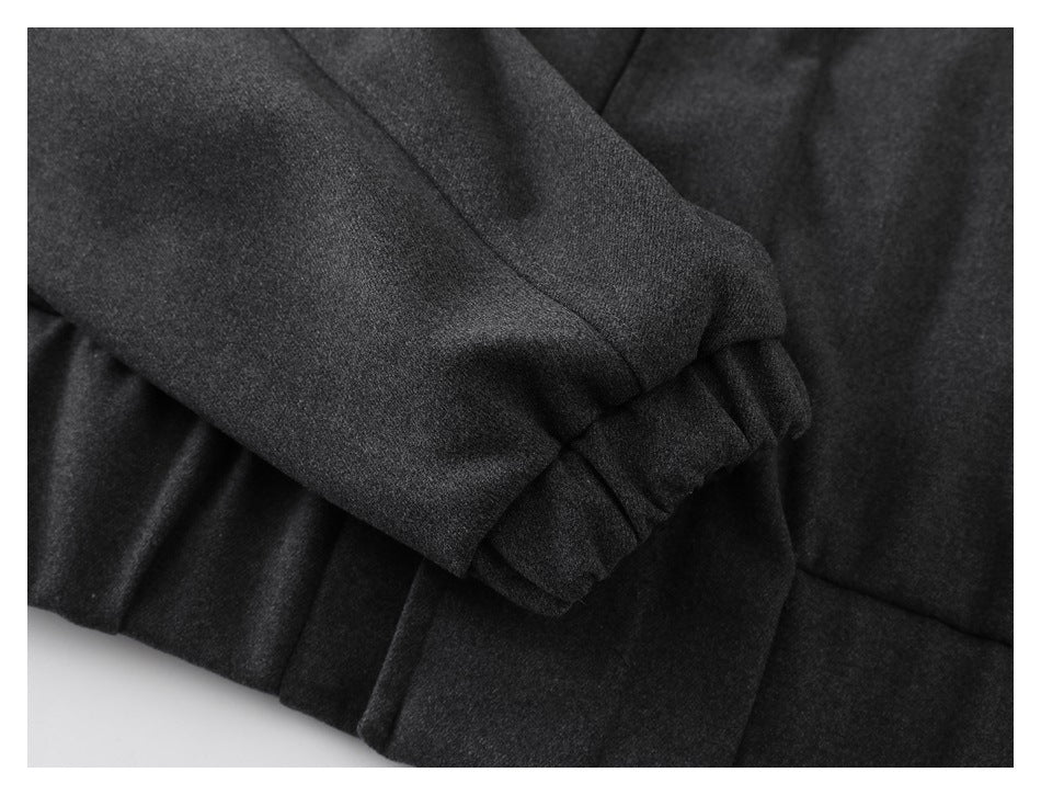 Close-up of a folded charcoal coat sleeve with a gathered cuff.
