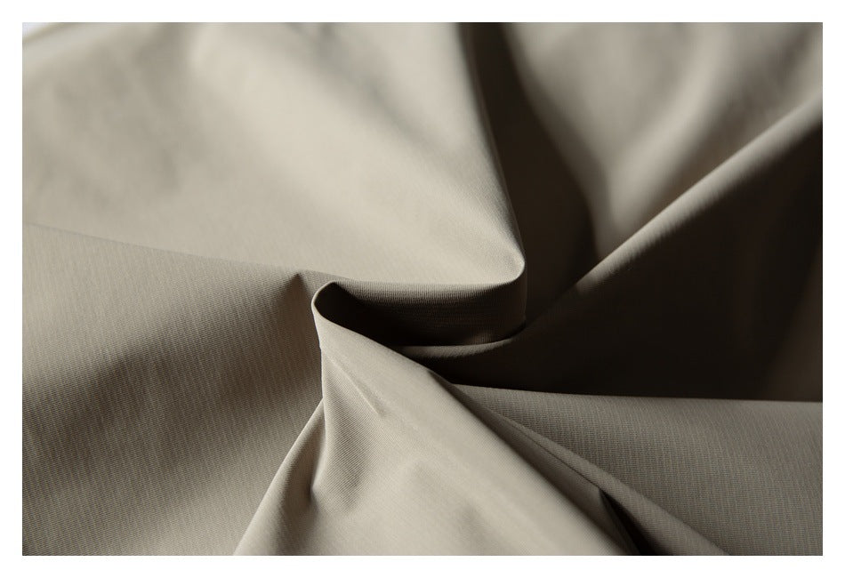 Macro view of taupe garment fabric gathered into soft folds, showing its fine surface texture.
